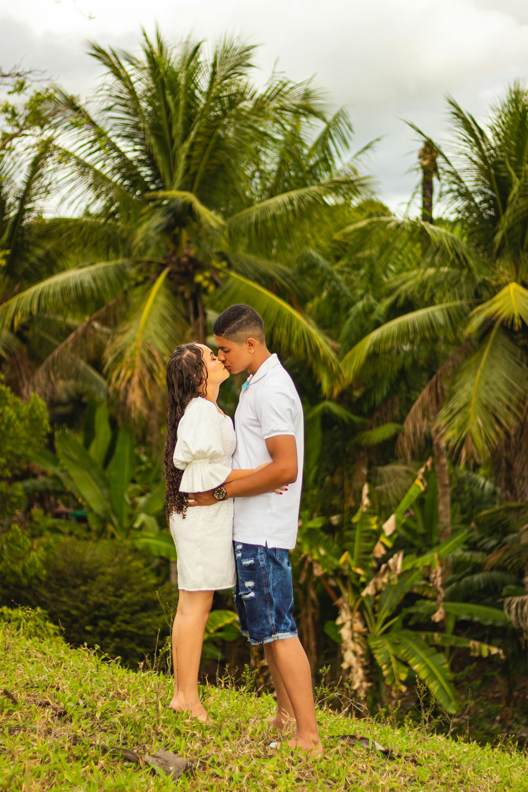 A couple shares a romantic moment surrounded by lush tropical greenery.