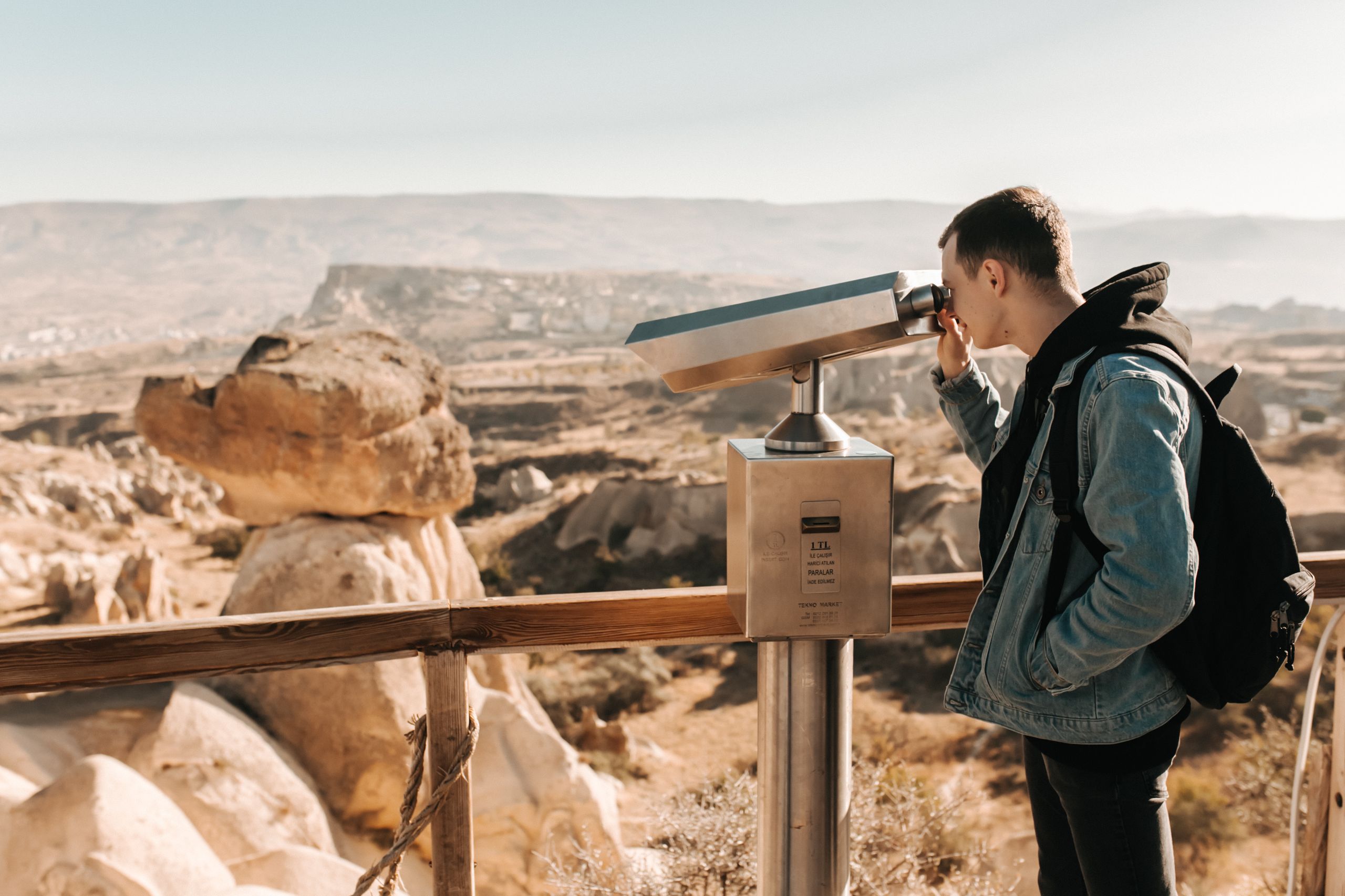 A man looks through a telescope, overlooking the unique rock formations in Cappadocia, Turkey.