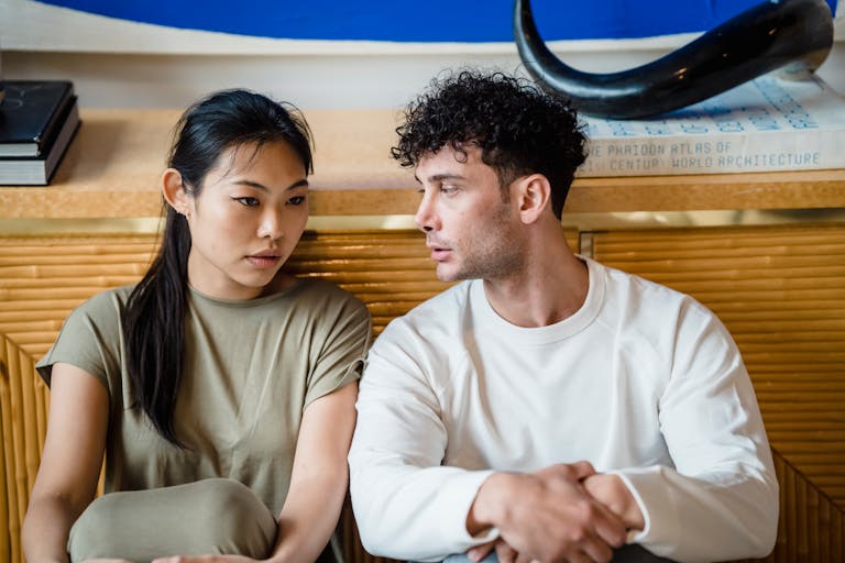 Asian woman and man sitting together having a serious conversation. Indoor setting.