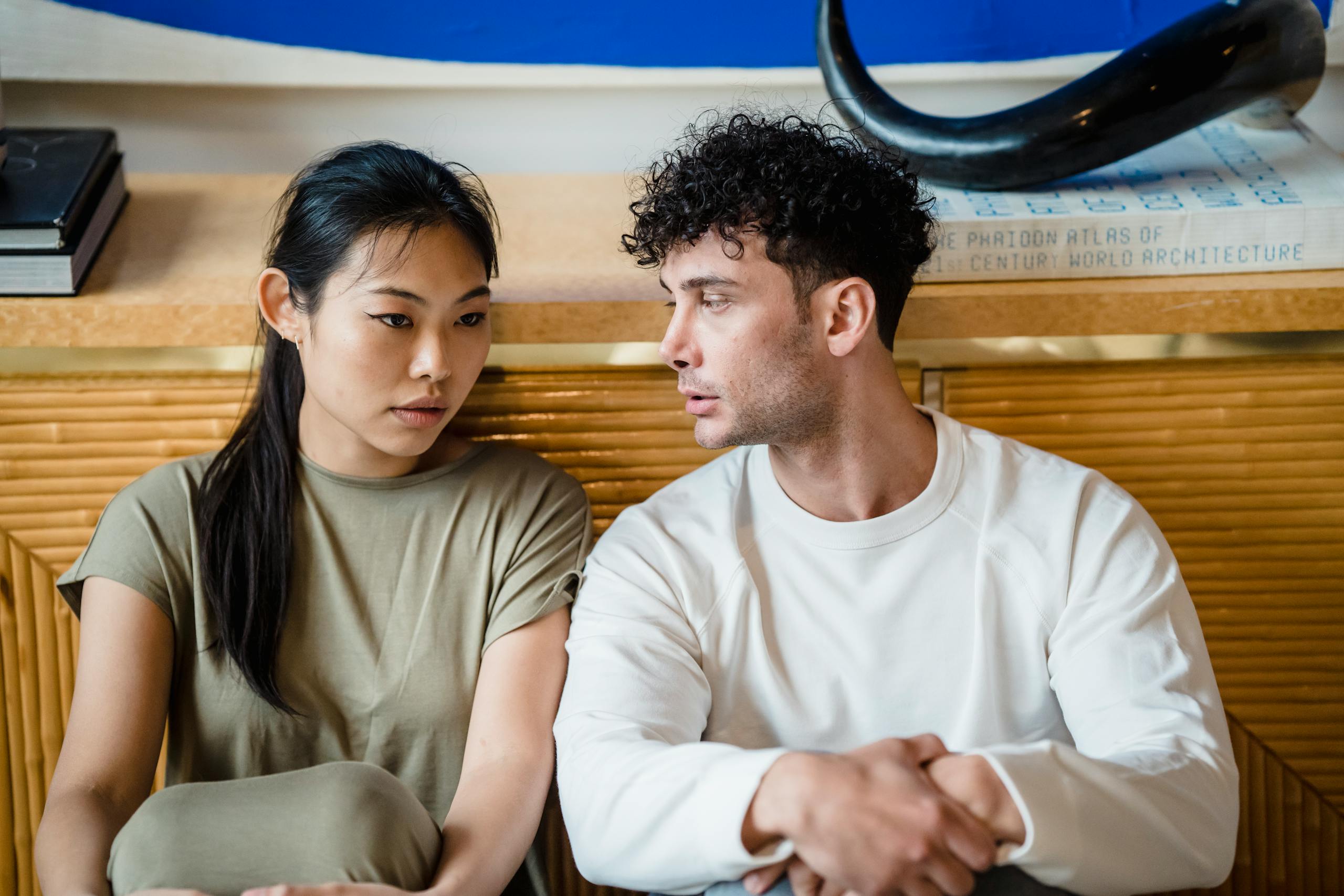 Asian woman and man sitting together having a serious conversation. Indoor setting.