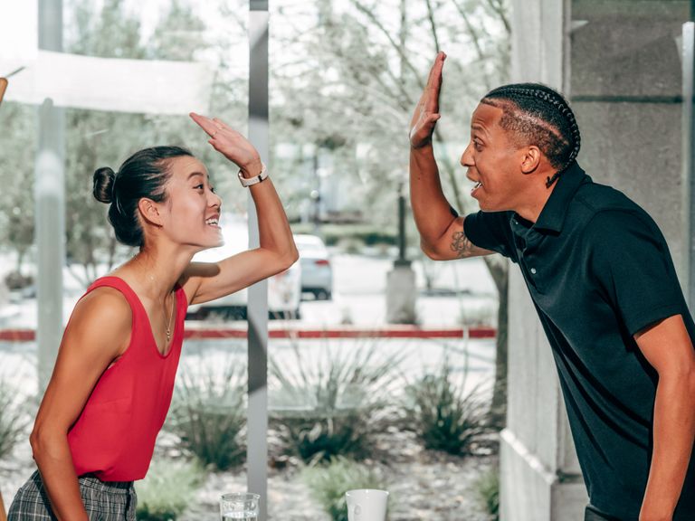 A joyful exchange between colleagues sharing a high-five inside a modern office.
