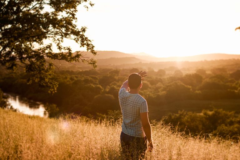 A man stands in a field, admiring the sunset over the scenic Brazilian countryside.