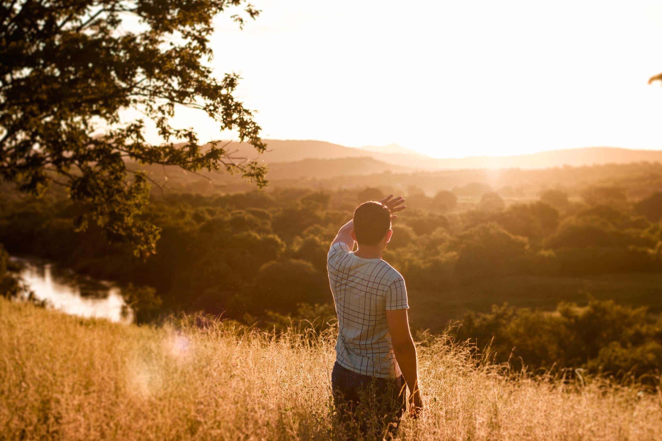A man stands in a field, admiring the sunset over the scenic Brazilian countryside.