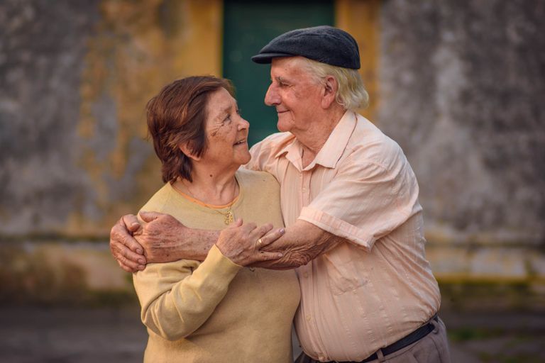 Charming elderly couple sharing a warm embrace outdoors, radiating love and joy.