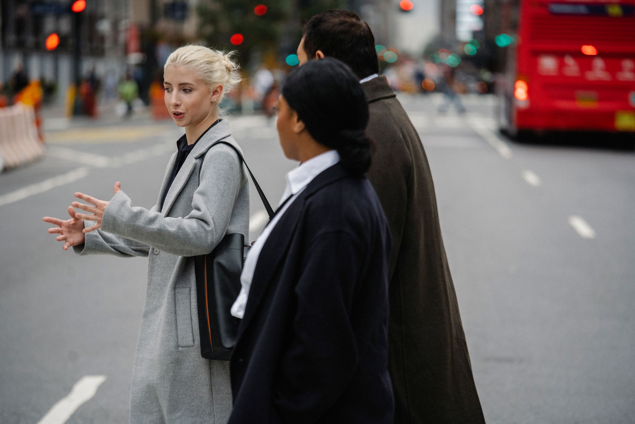 Side view of young female entrepreneur speaking with anonymous diverse colleagues while walking on city roadway