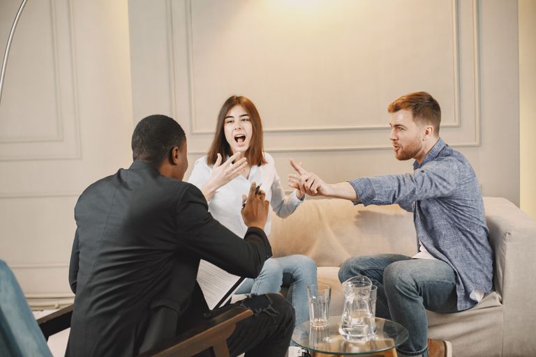 Three adults engaged in a lively discussion indoors, showcasing active communication and expression.